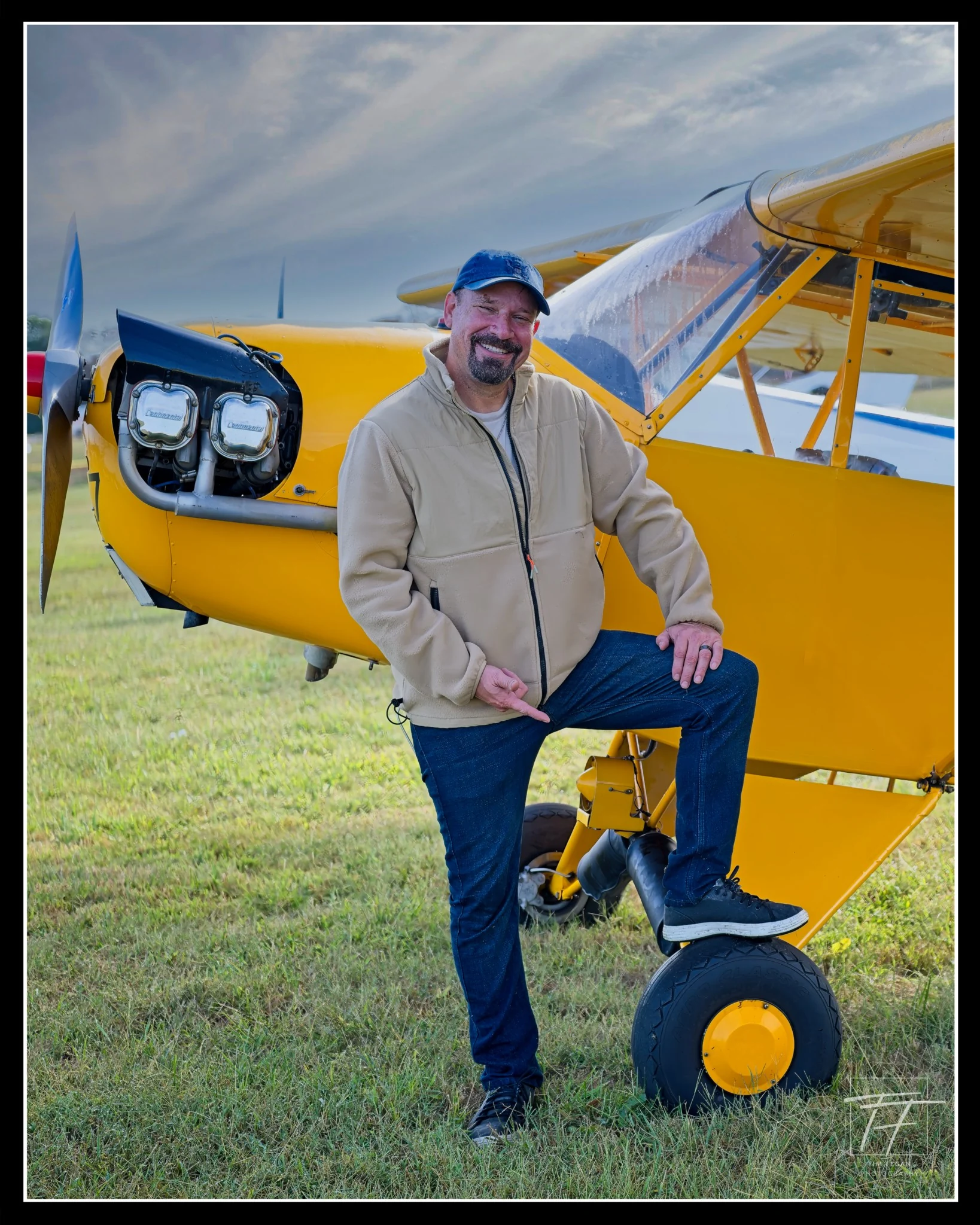 Grant Anderson smiling beside his yellow Piper J-3 Cub at Music City STOL