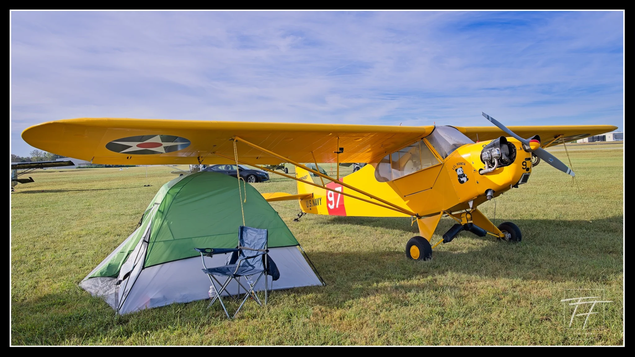 Yellow Piper J-3 Cub Li’l Panda parked on the grass at Music City STOL, with a small campsite in front